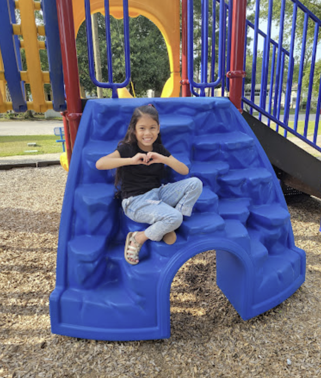 A resident child smiling on playground equipment at an MH Estates community