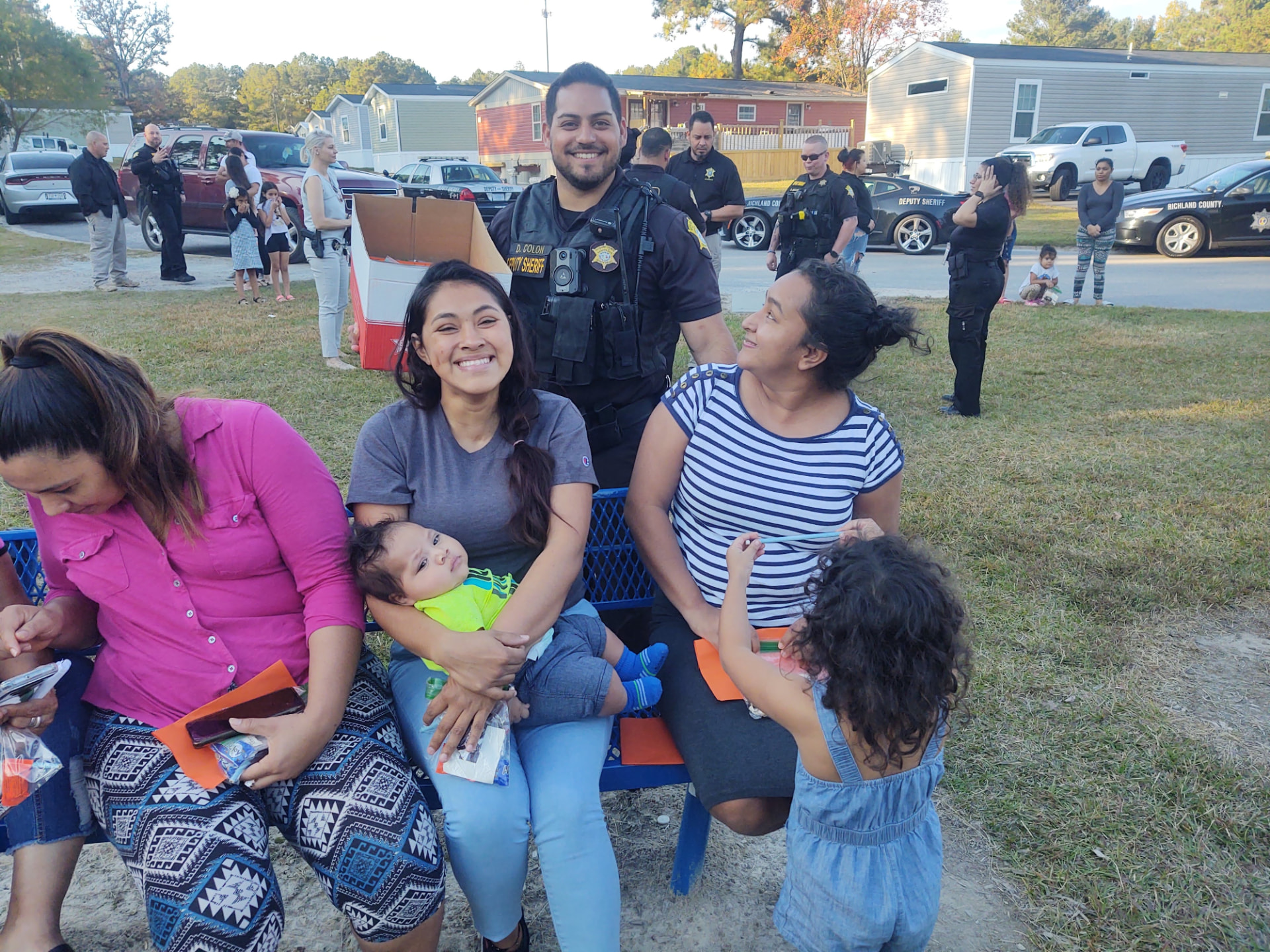 Residents and local sheriff's deputies gathered at a community event in an MH Estates manufactured housing community